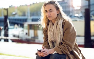 Sad woman sits on park bench | Featured image for family and domestic leave entitlements.