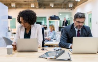 two business people working on laptops