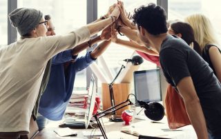 Team high fives in office | Featured image for culture vs strategy blog.