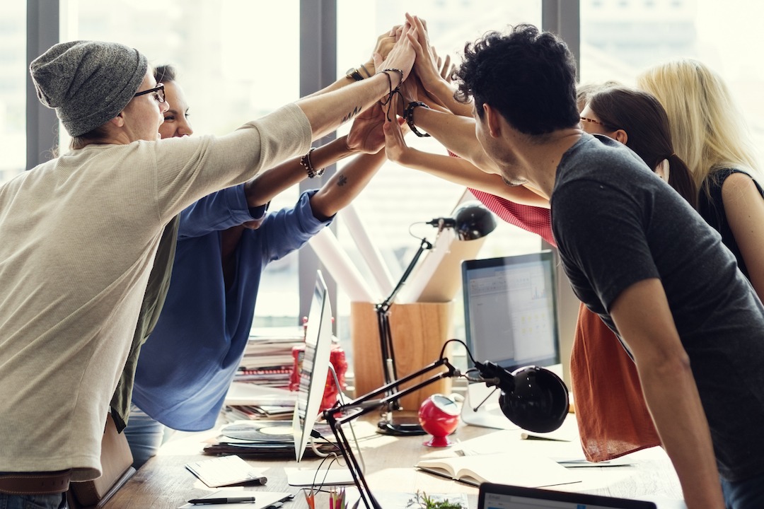 Team high fives in office | Featured image for culture vs strategy blog.