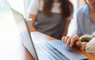 Ladies looking at a laptop screen - The importance of training and development in the workplace blog featured image